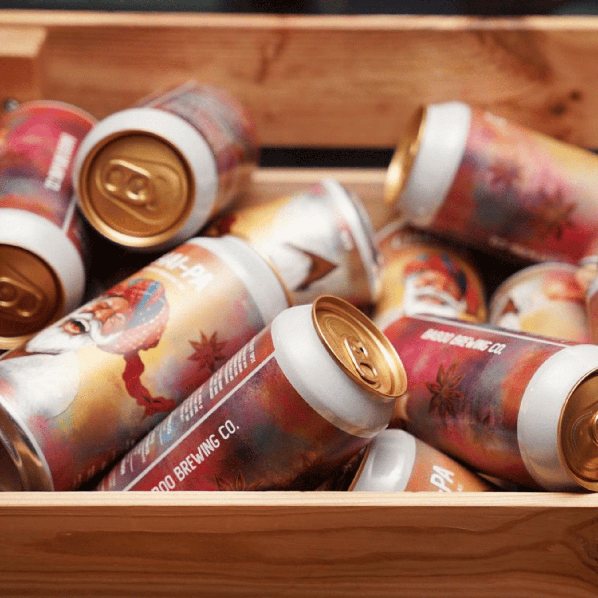 Beer cans with colorful labels in a wooden crate