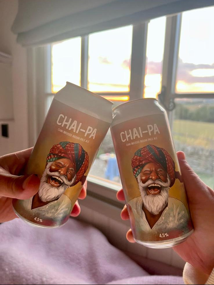 Two hands holding 'Chai-Pa' tea packages with a scenic window view in the background.