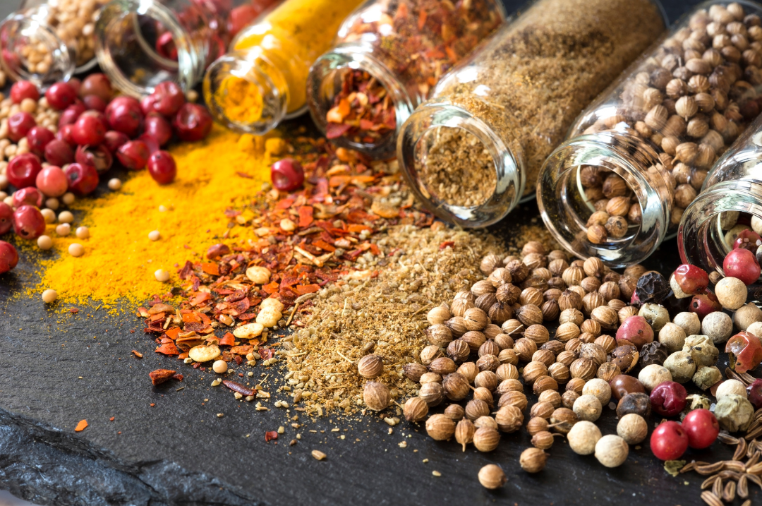 Spices and seasonings in glass containers on a dark surface